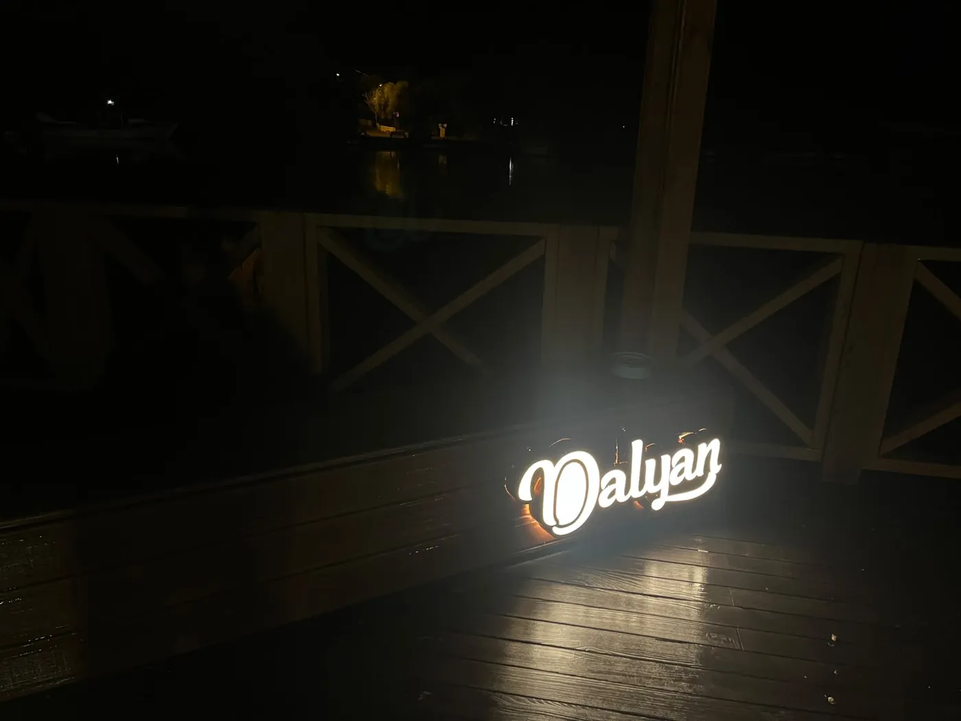 The illuminated Dalyan sign on the wooden deck by the river at night The illuminated Dalyan sign on the wooden deck by the river at night