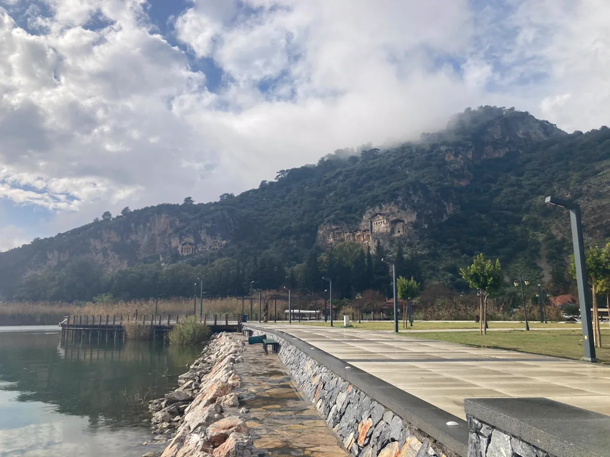 The riverside walkway in Dalyan with the rock tombs across the water The riverside walkway in Dalyan with the rock tombs across the water