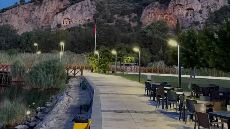 Der Uferweg in der Dämmerung, Restauranttische und die angestrahlten Gräber gegenüber