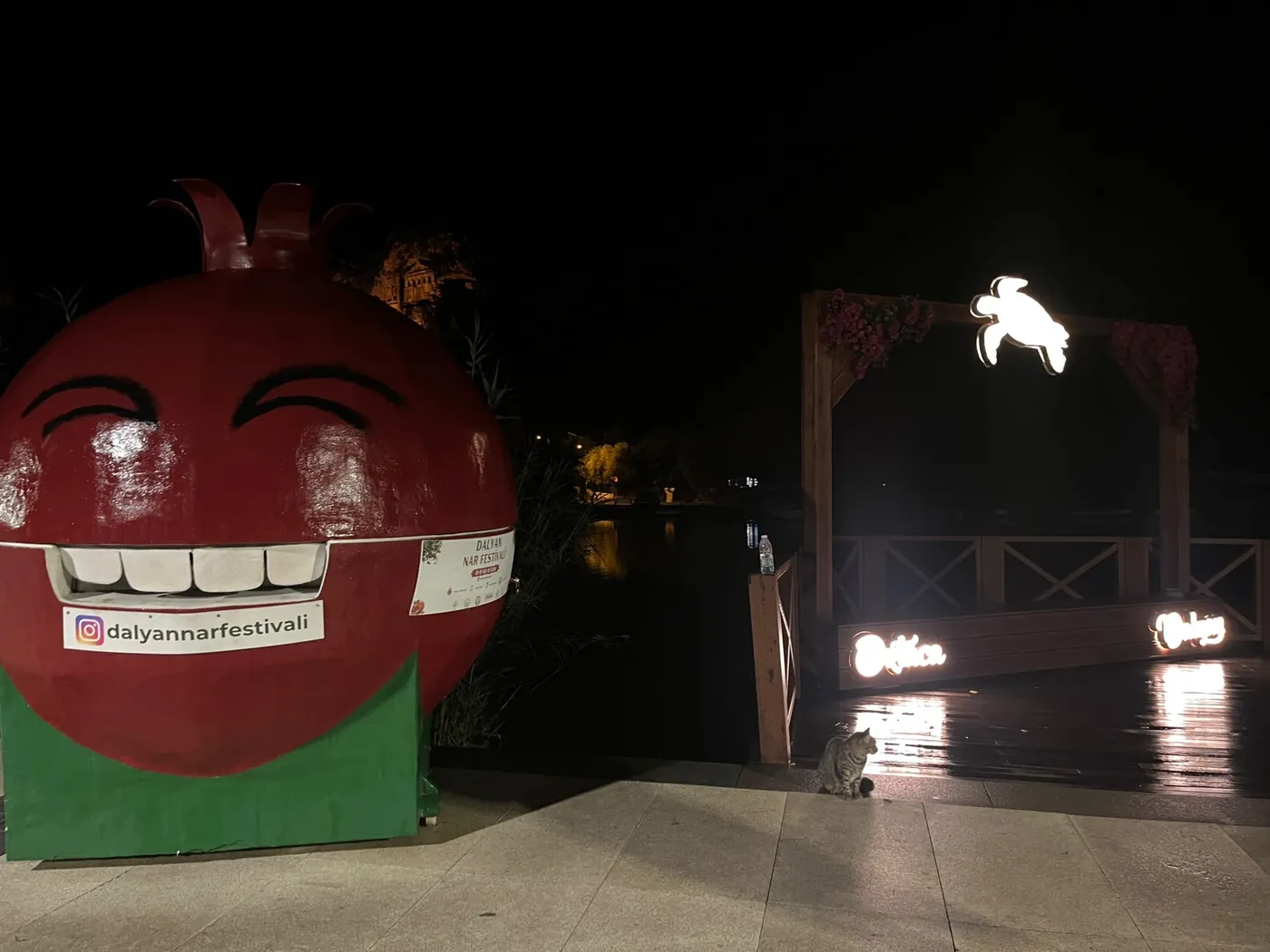 The pomegranate mascot and the lit wooden arch with its glowing turtle on the Dalyan riverfront The pomegranate mascot and the lit wooden arch with its glowing turtle on the Dalyan riverfront