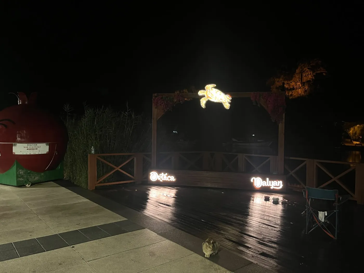 Der Schildkrötenbogen auf dem nassen Holzsteg, links das Festival-Maskottchen Der Schildkrötenbogen auf dem nassen Holzsteg, links das Festival-Maskottchen
