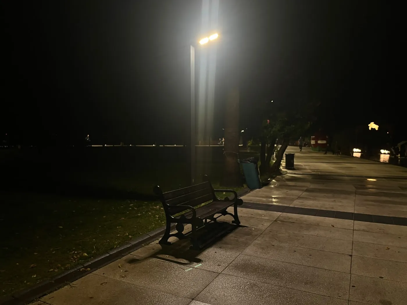 Lamp light on the empty riverside path after dark