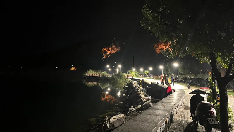 Gece nehir kenarı yolu, üstte aydınlatılmış mezarlar, yanında su Gece nehir kenarı yolu, üstte aydınlatılmış mezarlar, yanında su