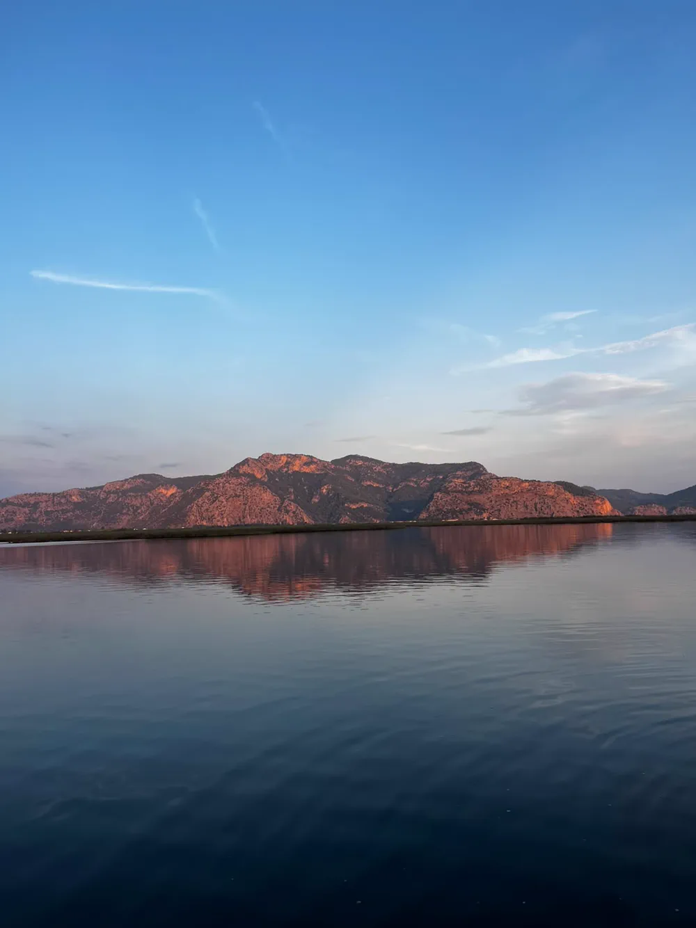 Mirror-still river water below pink mountains Mirror-still river water below pink mountains