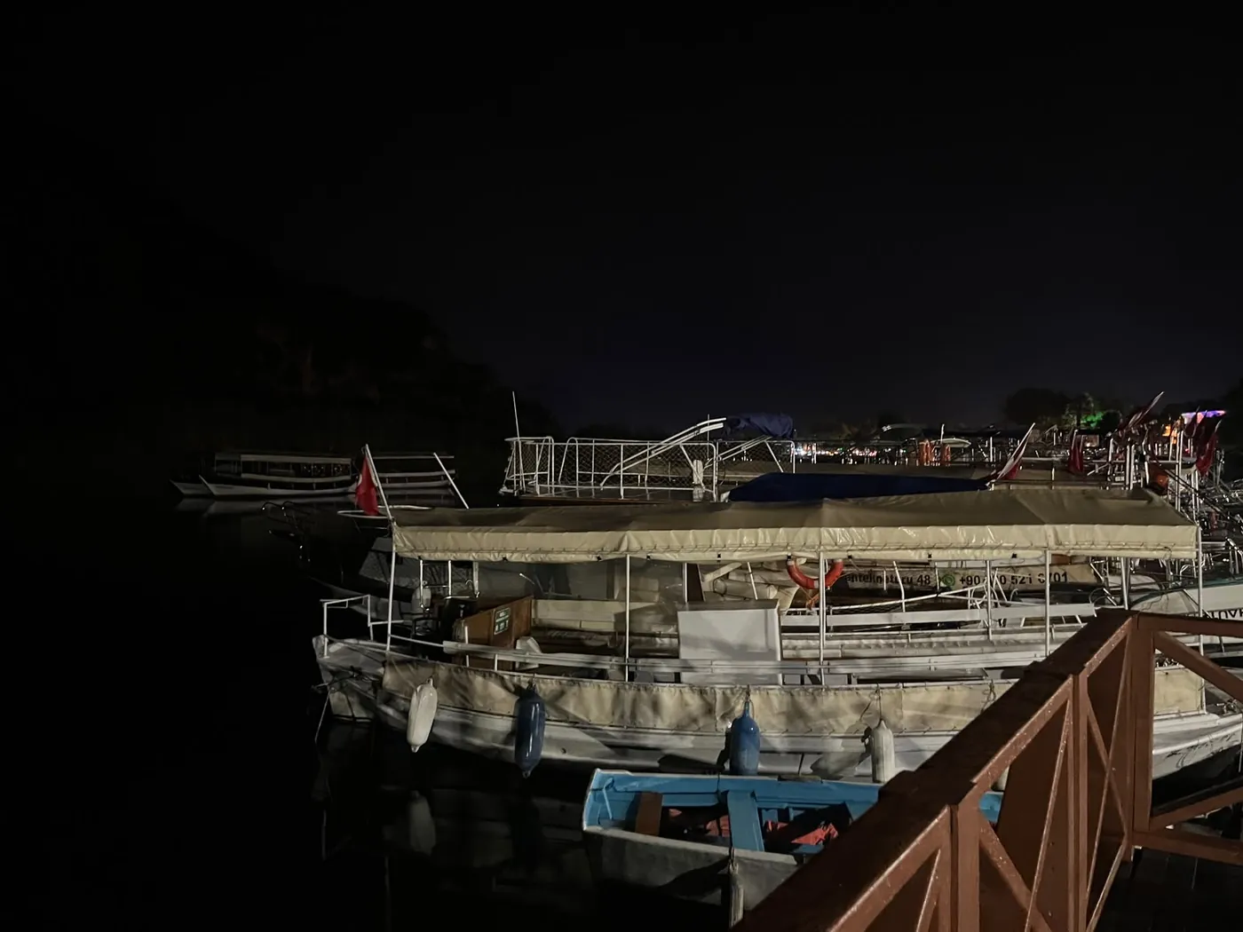 Eén houten rondvaartboot onder zijn kap, daarachter de donkere bergrug Eén houten rondvaartboot onder zijn kap, daarachter de donkere bergrug