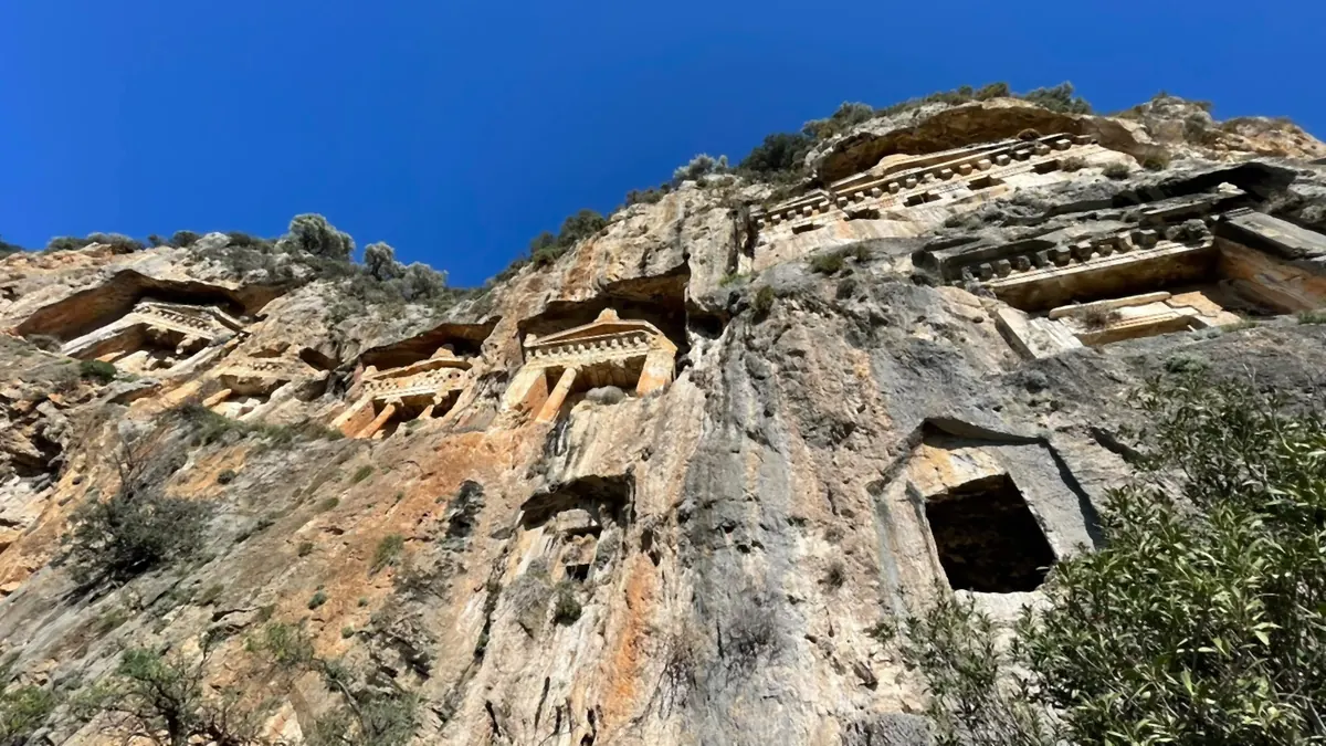 Looking straight up the cliff at the tombs from the foot of the rock Looking straight up the cliff at the tombs from the foot of the rock