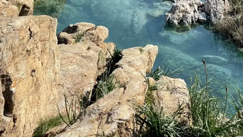 Travertenlerin üzerinden akan termal kaynak suyu, arkada ova ve dağlar Travertenlerin üzerinden akan termal kaynak suyu, arkada ova ve dağlar